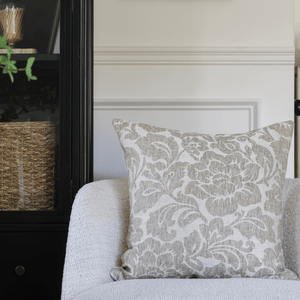 Delsi on a cream chair with a black bookcase in the background