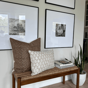 Emery and Jade Lumbar on a wooden bench in front of a gallery wall with photos