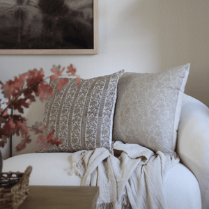 Isabelle and Louise in the corner of a cream sofa with a cream throw blanket underneath.
