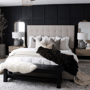 Various throw pillows on a white bed with a black accent wall.