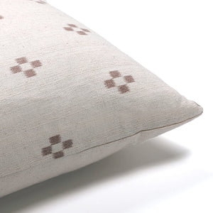 Corner of Dara pillow covering showing rust and ivory cross front and solid ivory backing.
