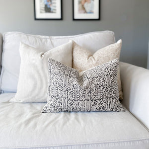Delilah, Laney, and Madison lumbar on white sofa with family photos on wall above couch.