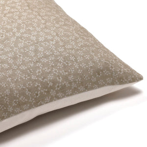 Side corner of the Neville pillow cover from Colin and Finn shown in sand background with linen floral motif.