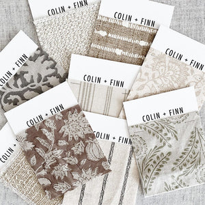 Colin and Finn fabric swatches stacked on top of each other sitting on a gray textile