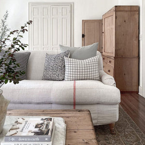 Madison and Imogen lumbar pillow covers from Colin and Finn on cream sofa with red vertical stripe and wood chester in background.