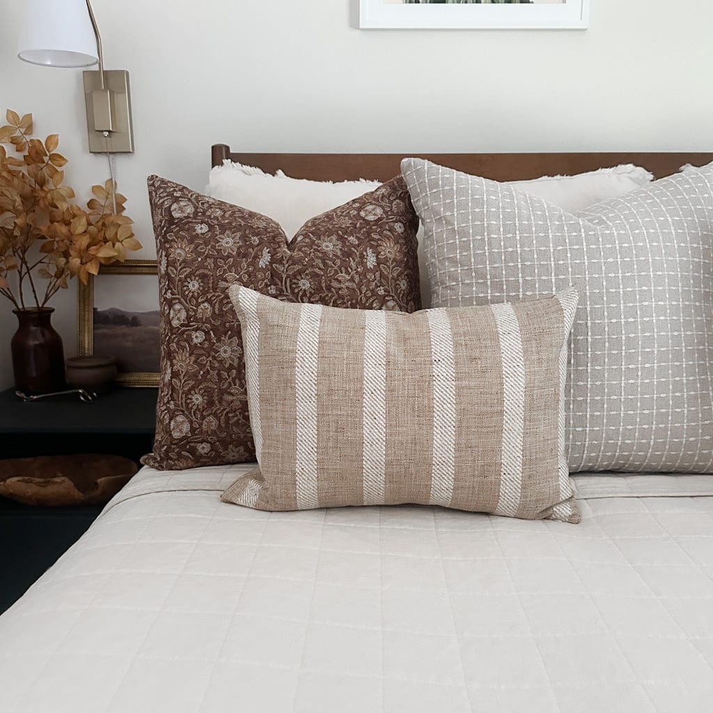 Esme, Agnes, and Caspian lumbar pillow covers from Colin and Finn on a neatly made bed with a cream quilt and wood headboard. Fall home decor sits on the side table.