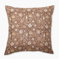 A square decorative pillow featuring a rich rust background adorned with intricate floral patterns in white and gold. The design includes various flowers and leaves, creating an elegant, sophisticated look. The edges of the pillow are clean and neatly finished.