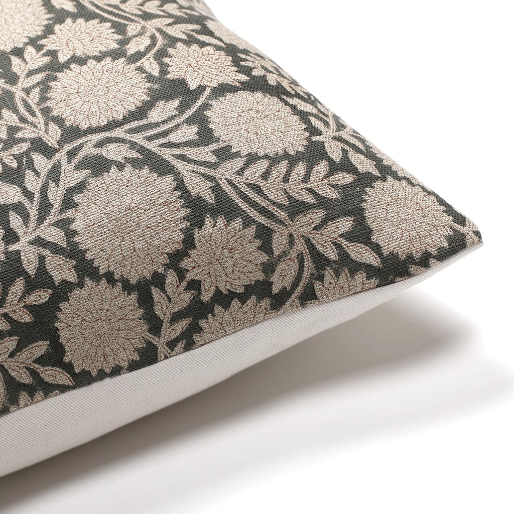 A decorative pillow with a dark fabric cover featuring an intricate floral and leaf pattern in light beige. The corner of the pillow is shown against a white background.