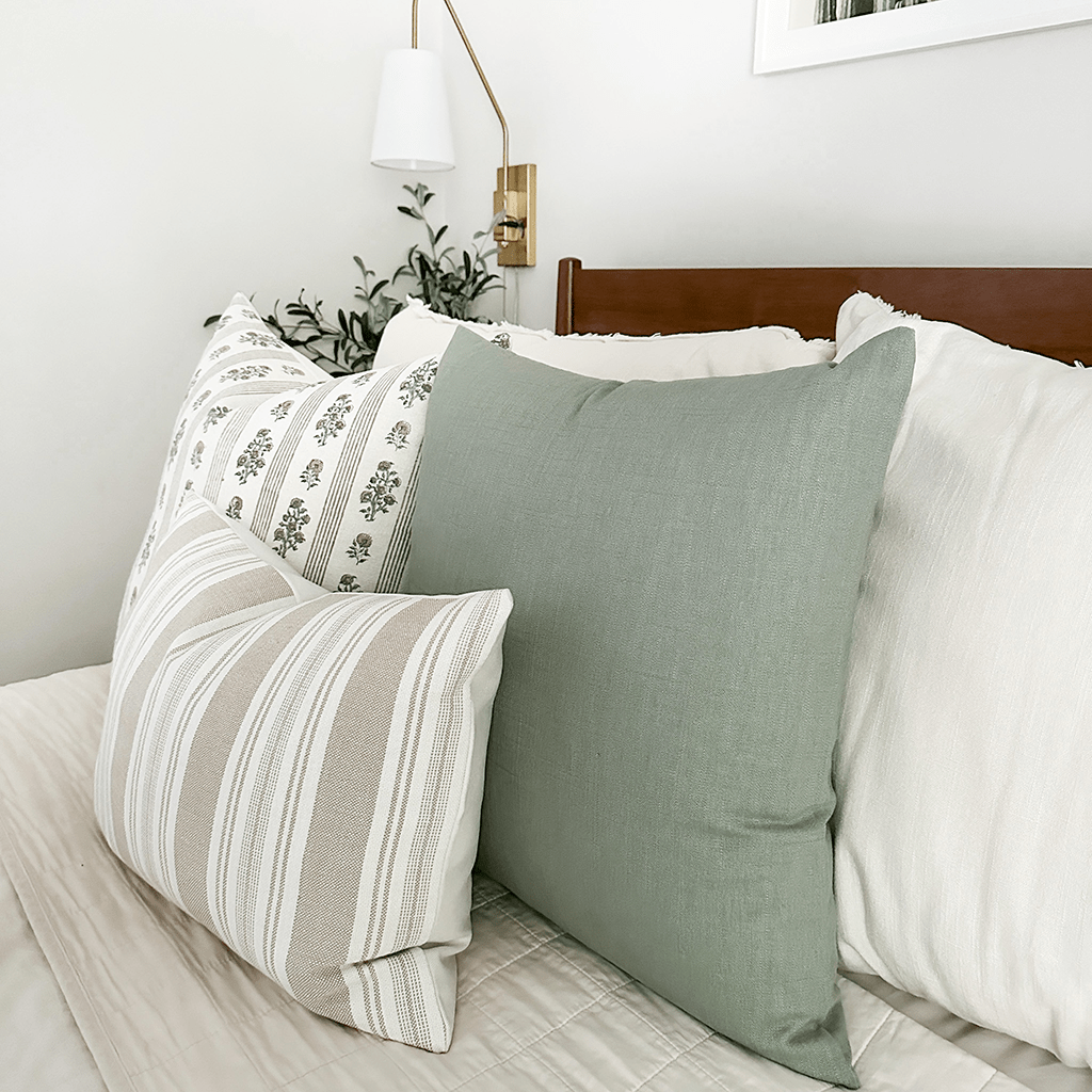 Side view of Colleen pillow cover showing the sage green on the front and back. Paired next to Leighton, Odin lumbar, on a white bed.