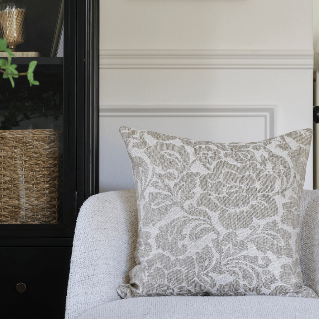 Delsi on a cream chair with a black bookcase in the background