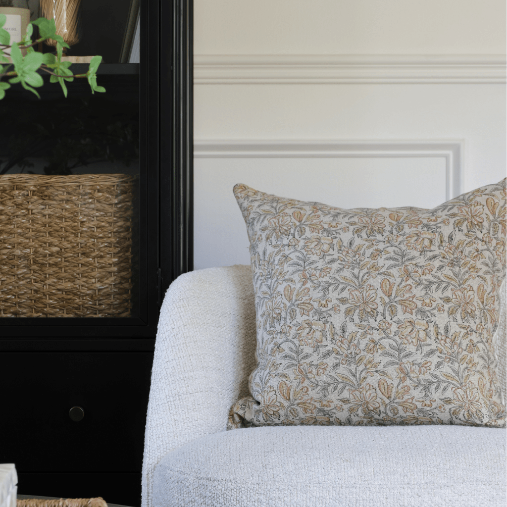 Elain on a cream chair with a black bookcase in the background