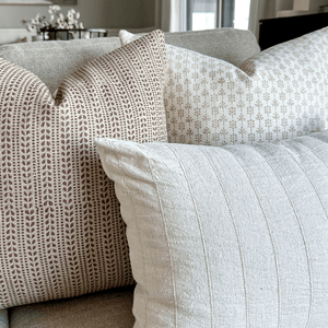 A close up of Odette, Ester, and Logan Lumbar in the corner of a grey sofa