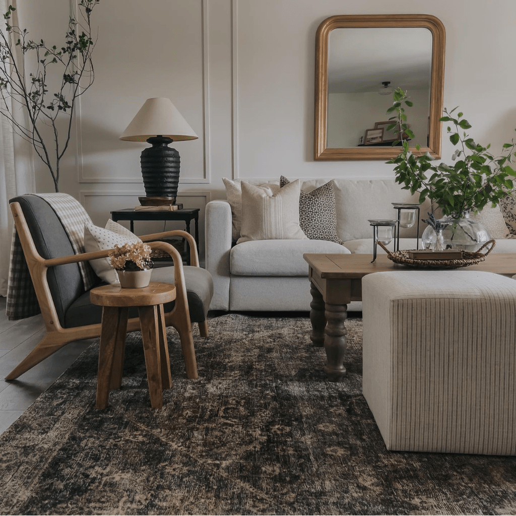 A living room with a side chair in the foreground with the Elodie Lumbar pillow and a beige couch in the background with the Neville Mocha, Kinsey, and Livvy pillows
