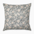 A square pillow with a light blue-green background features an intricate pattern of white and beige roses with green leaves and small brown branches. The floral design is spread evenly across the entire surface of the pillow.