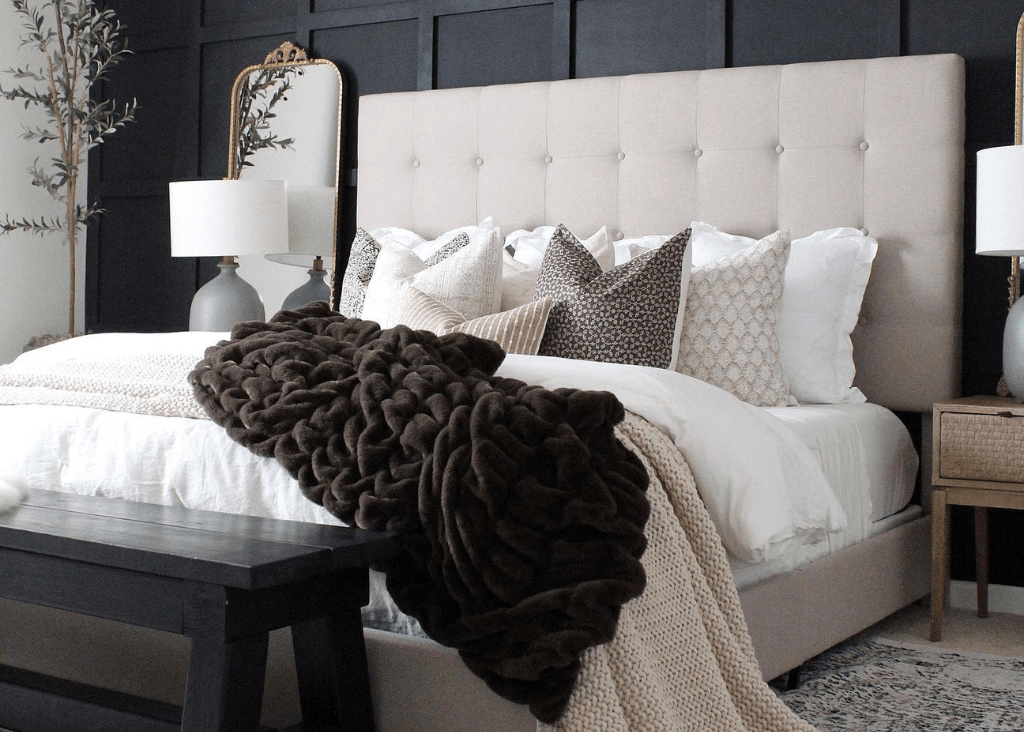 A cream bed against a black wall with a dark brown blanket and Madison, Neville Mocha, Livvy, Karina, Jade, Logan, and Bardot Lumbar pillows