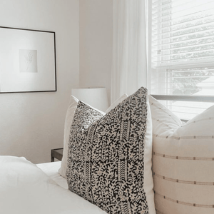 A closeup of Madison and Rory pillows on a bed in front of a window