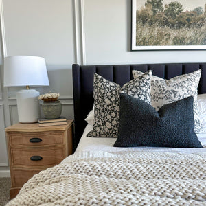 Magnolia, Felix, and Onyx lumbar throw pillows from Colin and Finn on white bed with black headboard.