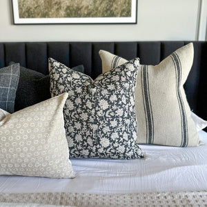 Various black and taupe throw pillows from Colin and Finn on bed with black headboard.