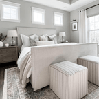 A bedroom with a gray bed in the center of the room with Penelope, Felicity, Eloise, and Winston Lumbar. Two striped ottomans at the foot of the bed. 