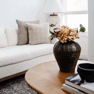 Waylon and Wesley pillows from Colin +Finn on a cream-colored couch with a vase with flowers in the foreground