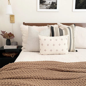 Benedict, Laney, and Dara lumbar pillow covers on white bedding with taupe throw blanket.