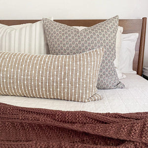 Ella pillow cover with Bardot long lumbar on white bed with maroon throw blanket in front of pillows.