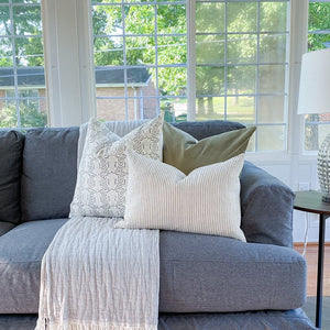 Emma, Bay leaf velvet, and Laney lumbar pillow covers from Colin and Finn on gray couch in sunroom.
