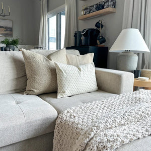 Kinsey, Neville in sand, and Elodie lumbar on a gray sofa with lamp on side table.