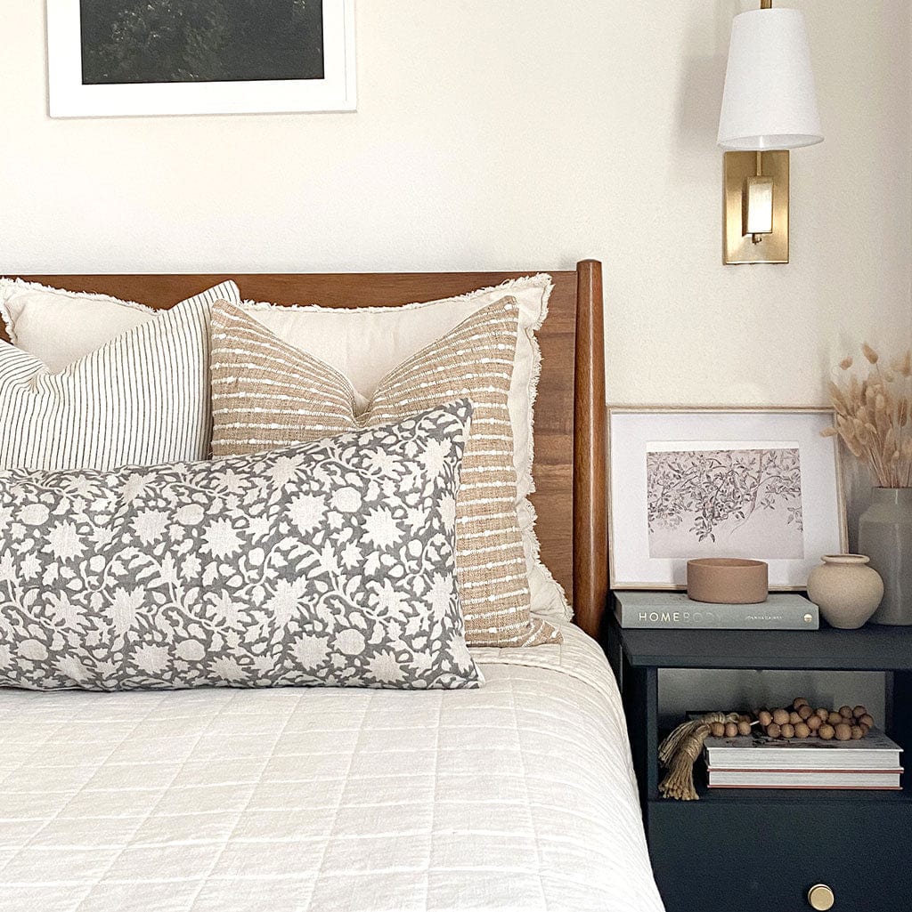 Laney, Bardot, and large Sawyer lumbar pillow covers on cream quilt with a picture frame on side table.