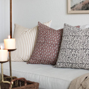 Leo throw pillow on a light grey sofa with Serena and Madison throw pillows. Candles in front of the sofa