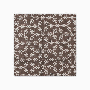 Neville Mocha fabric swatch from Colin and Finn. Cream flowers on a brown background