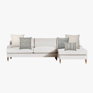 Pacific pillow combination on a cream sectional sofa with wood legs on a white background as a mockup.