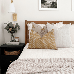 Remington, Laney, and Saffron lumbar pillows from Colin and Finn on white bed with wood headboard.