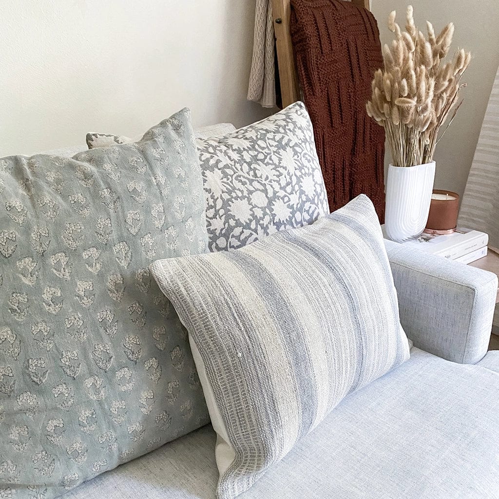Sawyer, Eloise, and Felicity lumbar pillow covers on white sofa. Wheat grass floral arrangement on side table with maroon blanket on ladder in background.