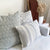 Sawyer, Eloise, and Felicity lumbar pillow covers on white sofa. Wheat grass floral arrangement on side table with maroon blanket on ladder in background.