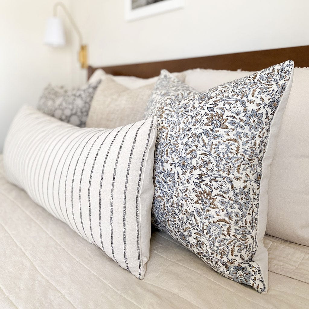Penelope and Winston long lumbar on a white bed with wood headboard.