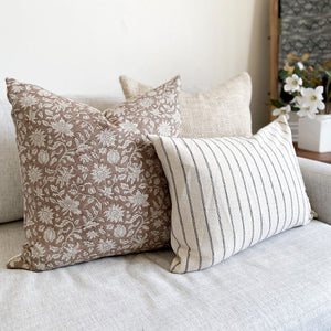 Weston, Eleanor in natural, and Winston lumbar pillow covers on white sofa with floral arrangement on side table.