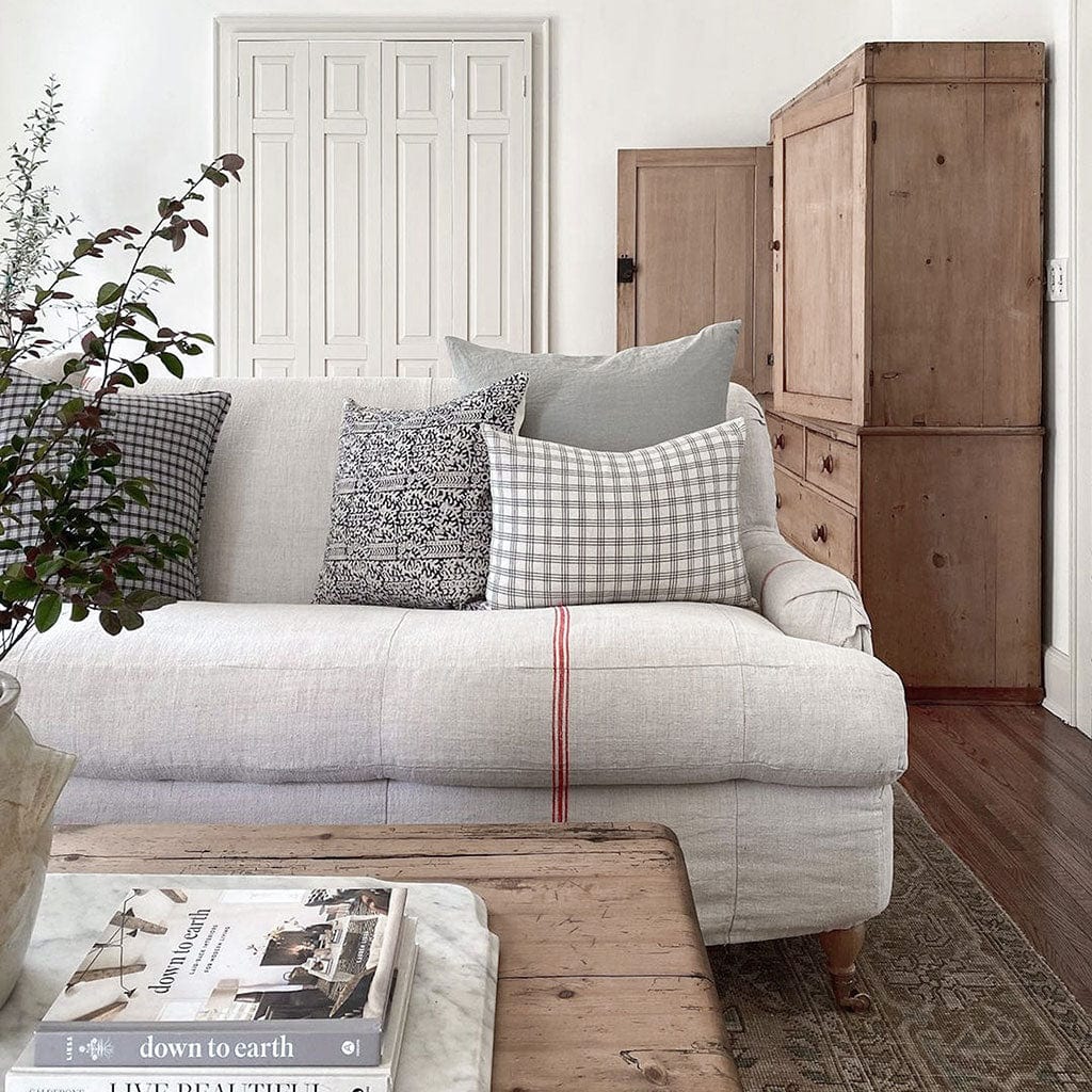 Madison and Imogen lumbar pillow covers from Colin and Finn on cream sofa with red vertical stripe and wood chester in background.