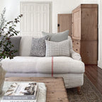 Madison and Imogen lumbar pillow covers from Colin and Finn on cream sofa with red vertical stripe and wood chester in background.